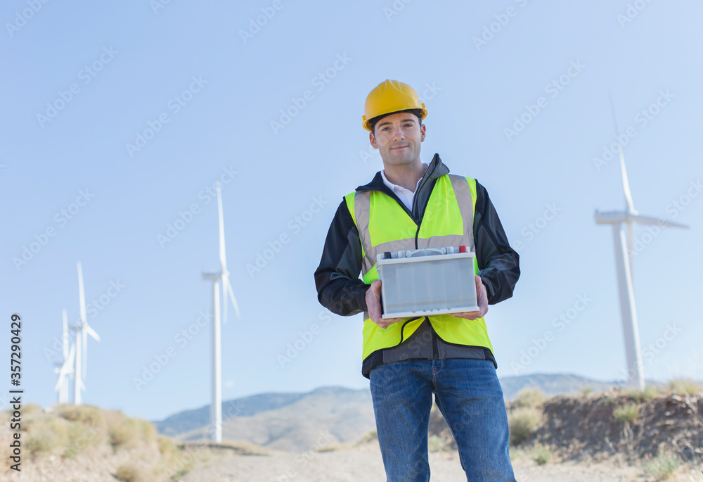 Worker standing by wind turbines in rural landscape Worker standing by wind turbines in rural landscape