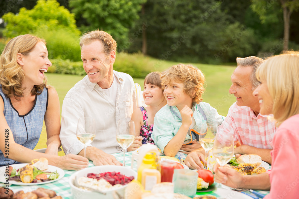 Multi-generation family enjoying lunch in backyard Multi-generation family enjoying lunch in backyard