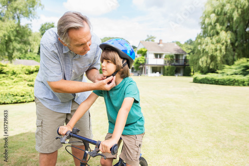Papier peint Grandfather adjusting bicycle helmet on grandson