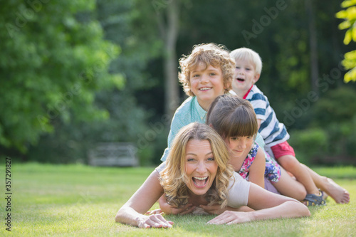 Children laying on mother in grass