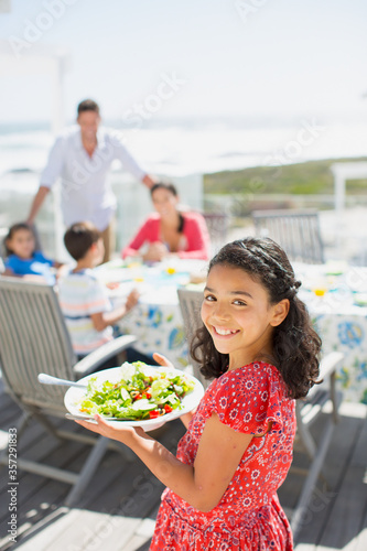 Smiling girl carrying salad bowl on sunny patio