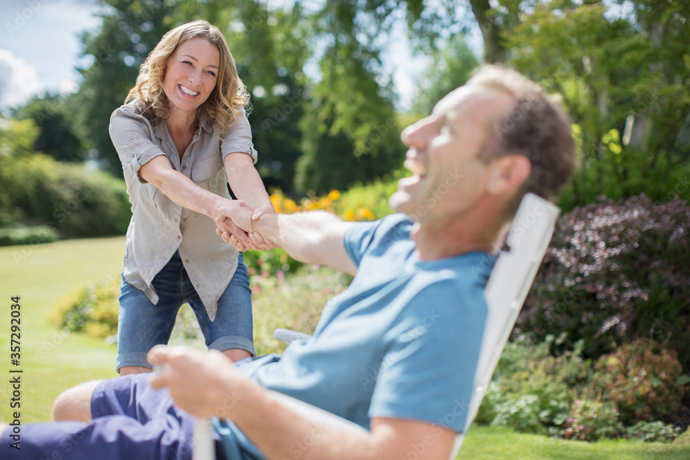 Woman pulling boyfriend out of chair in backyard Woman pulling boyfriend out of chair in backyard