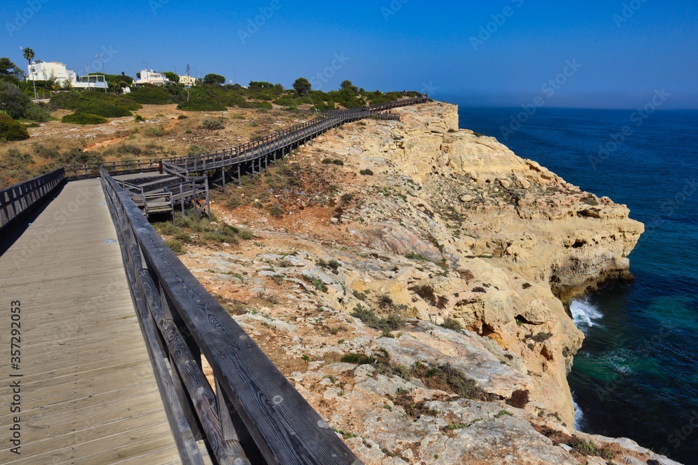 Carvoeiro Boardwalk with Atlantic Ocean Splashing in the Cliff in South Portugal. Wooden Path in Algarve.