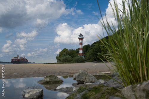 Leuchtturm am Elbstrand in Rissen mit vorbeifahrendem Containerschiff
