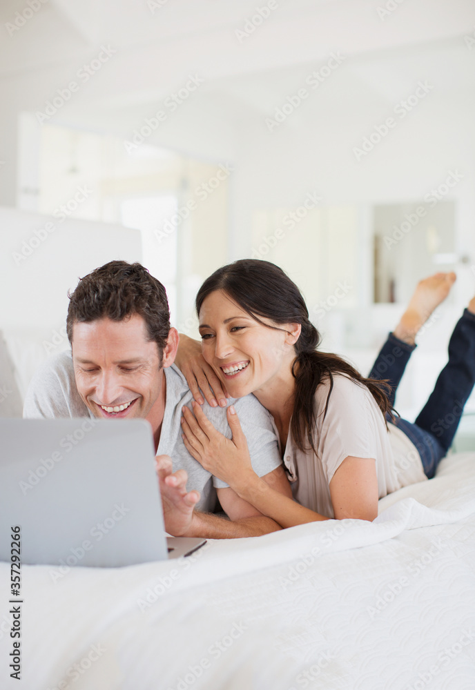 Couple using laptop on bed Couple using laptop on bed