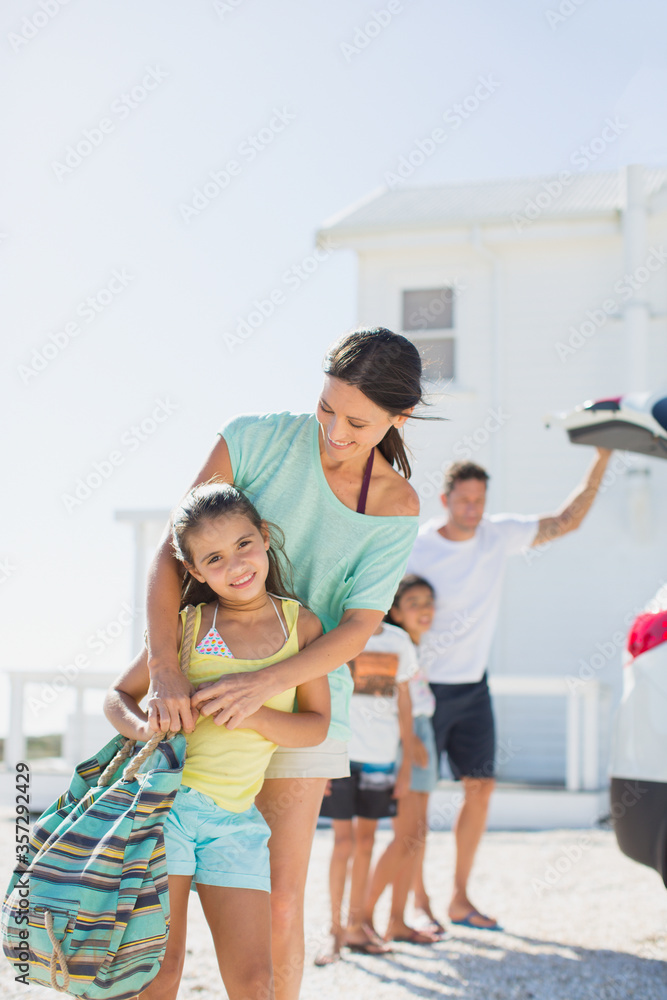 Mother and daughter hugging in sunny driveway Mother and daughter hugging in sunny driveway