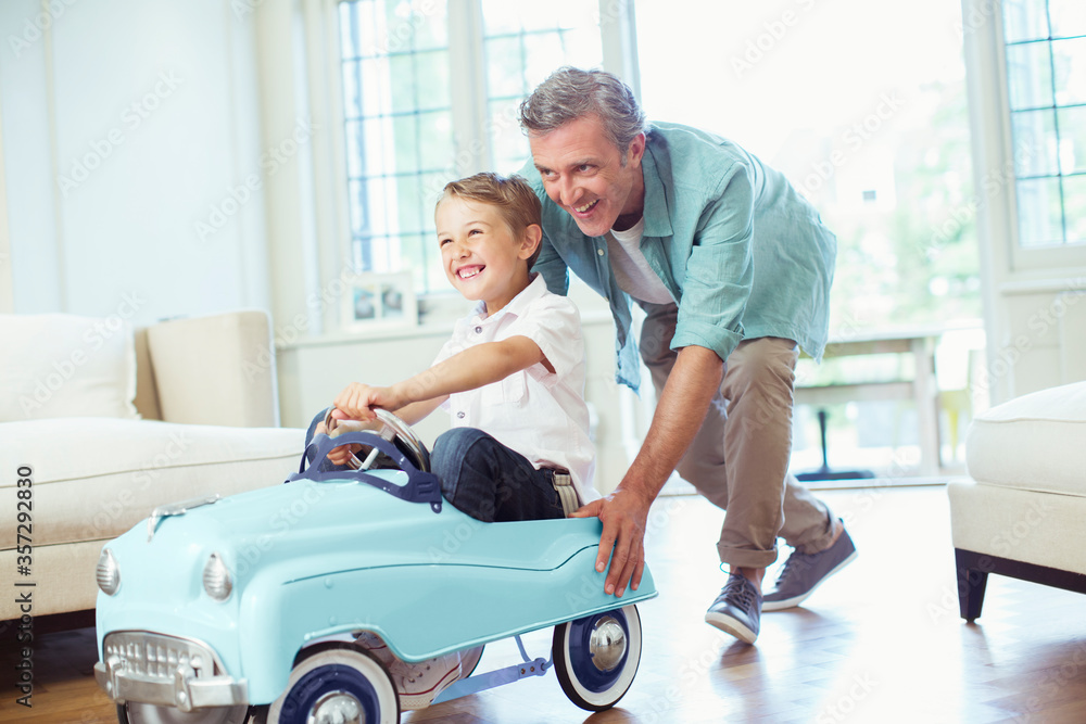 Father pushing son in toy car Father pushing son in toy car