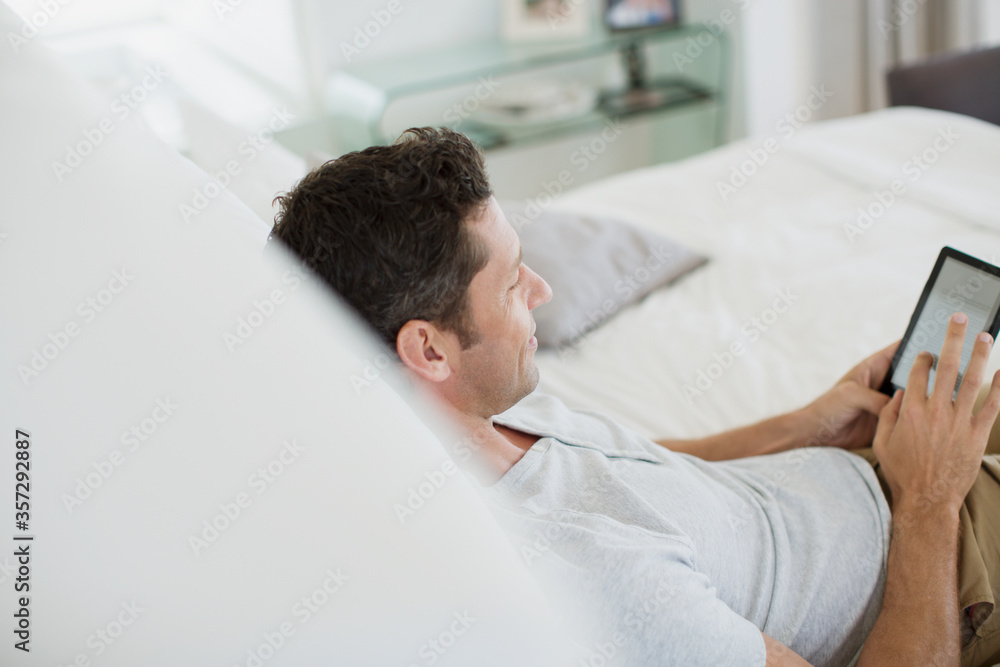Fototapeta premium Man using digital tablet on bed