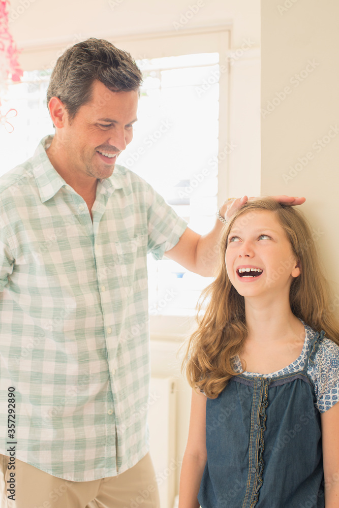Father measuring daughter's height on wall Father measuring daughter's height on wall