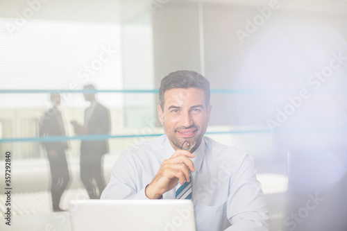 Portrait of confident businessman at laptop in office