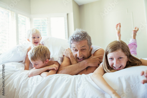 Father and children relaxing on bed © Paul Bradbury/KOTO