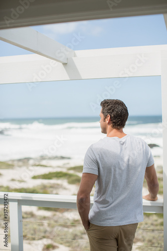 Fotografija Man looking at ocean view from balcony