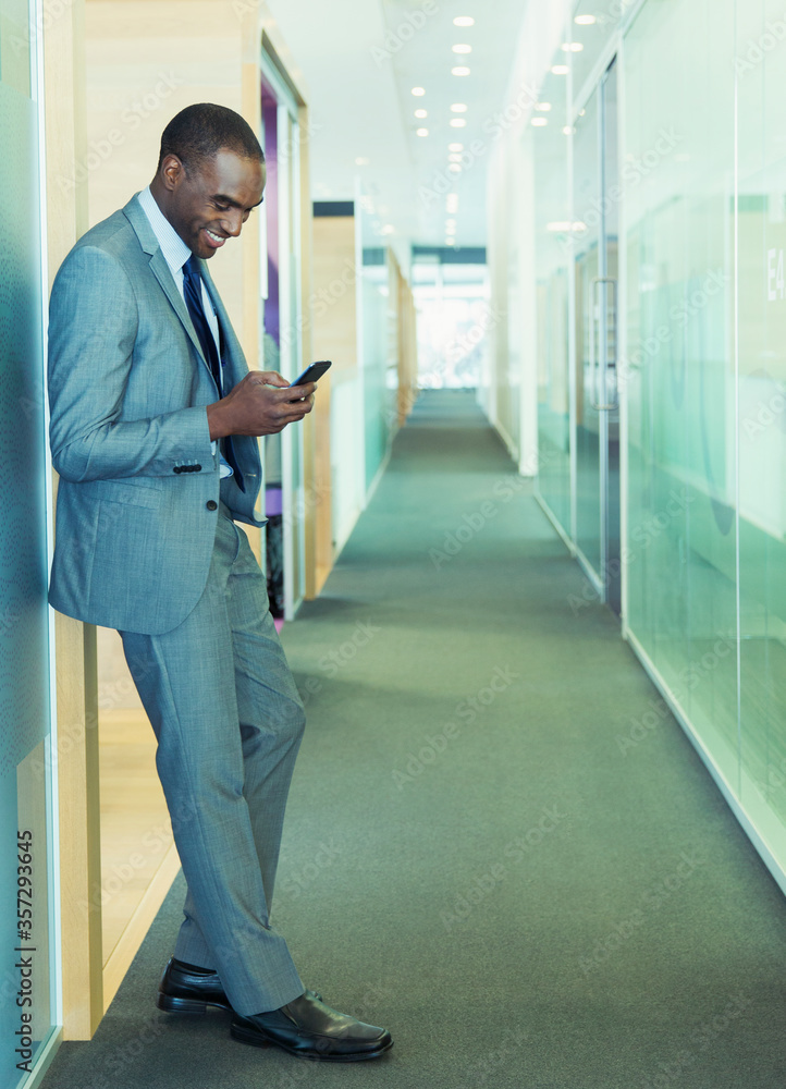 Fotografie Businessman using cell phone in office corridor