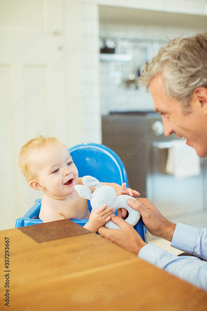 Father playing with baby in high chair Father playing with baby in high chair
