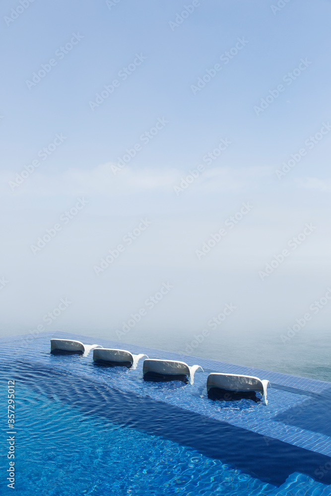 Lawn chairs in infinity pool overlooking ocean