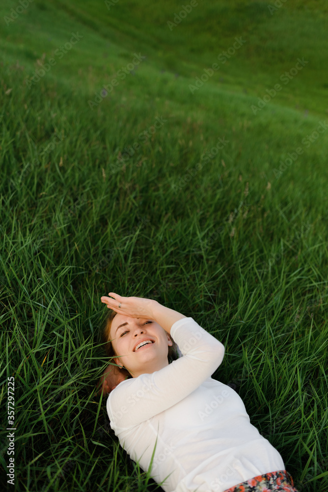 Young pretty woman lying on the grass at summer sunset. High quality photo Young pretty woman lying on the grass at summer sunset. High quality photo