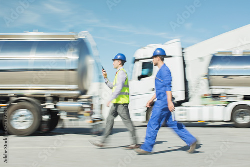 Workers walking past stainless steel milk tankers