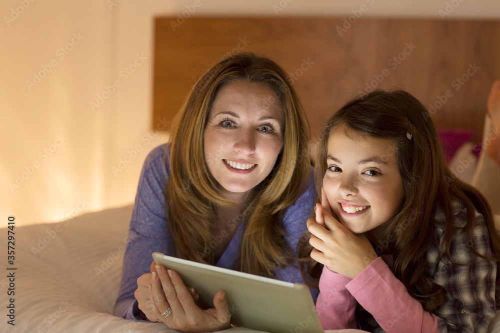 Mother and daughter using digital tablet on bed Mother and daughter using digital tablet on bed