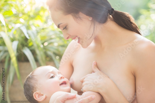 Mother breast-feeding baby boy outdoors
