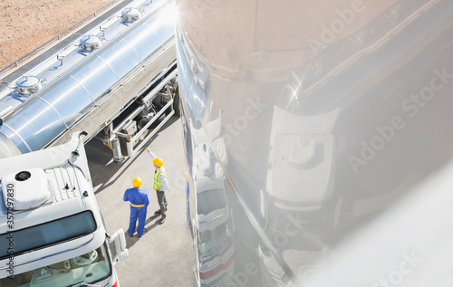 Workers talking next to stainless steel milk tanker