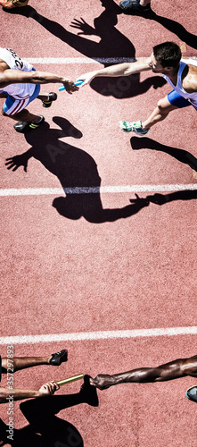Obraz na płótnie Relay runners handing off baton on track