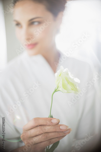 Close up of woman in bathrobe holding white rose
