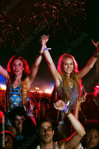 Cheering women on mens shoulders at music festival
