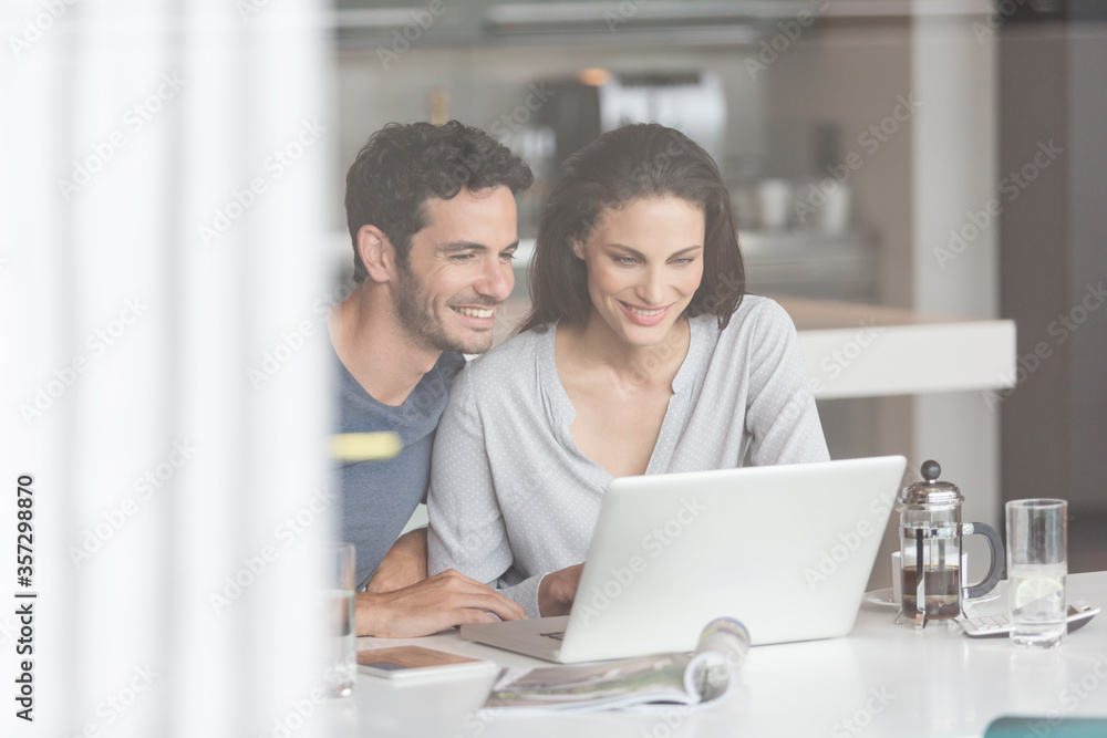 Couple using laptop at table