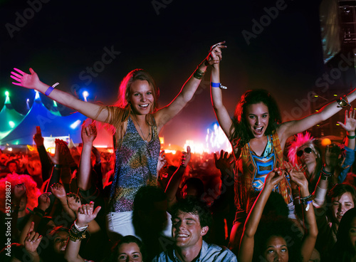 Photo Cheering women on mens shoulders at music festival