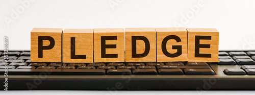 the word of PLEDGE on building blocks concept, black keyboard background. photo