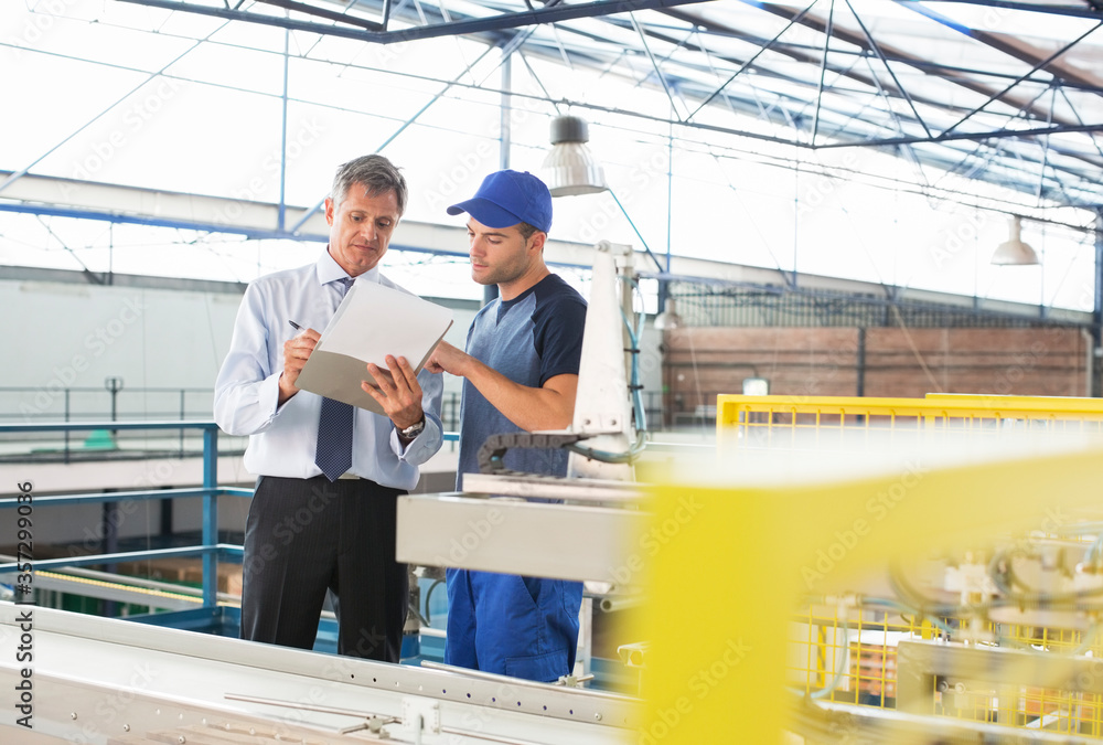 Supervisor and worker with clipboard in food processing plant Supervisor and worker with clipboard in food processing plant