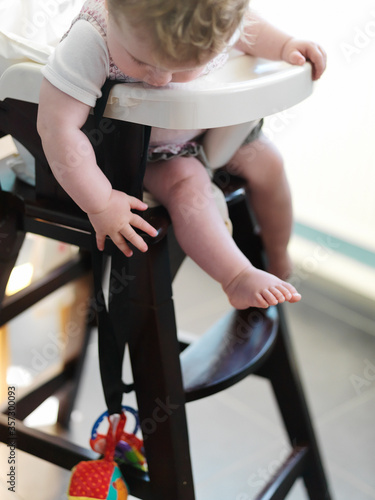 Baby girl in high chair reaching for toy 