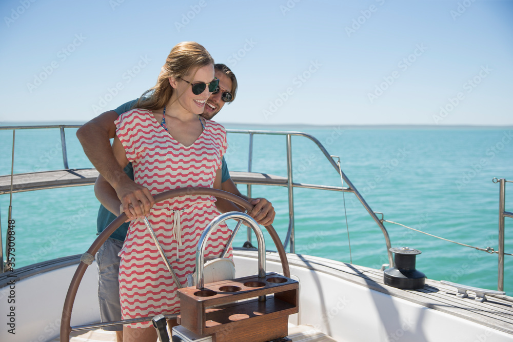 Couple steering sailboat together 