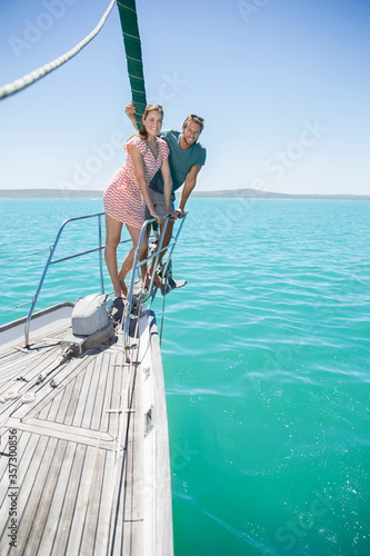 Couple standing on front of sailboat 