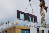 Installation of prefabricated walls at the construction site. The crane moves concrete elements