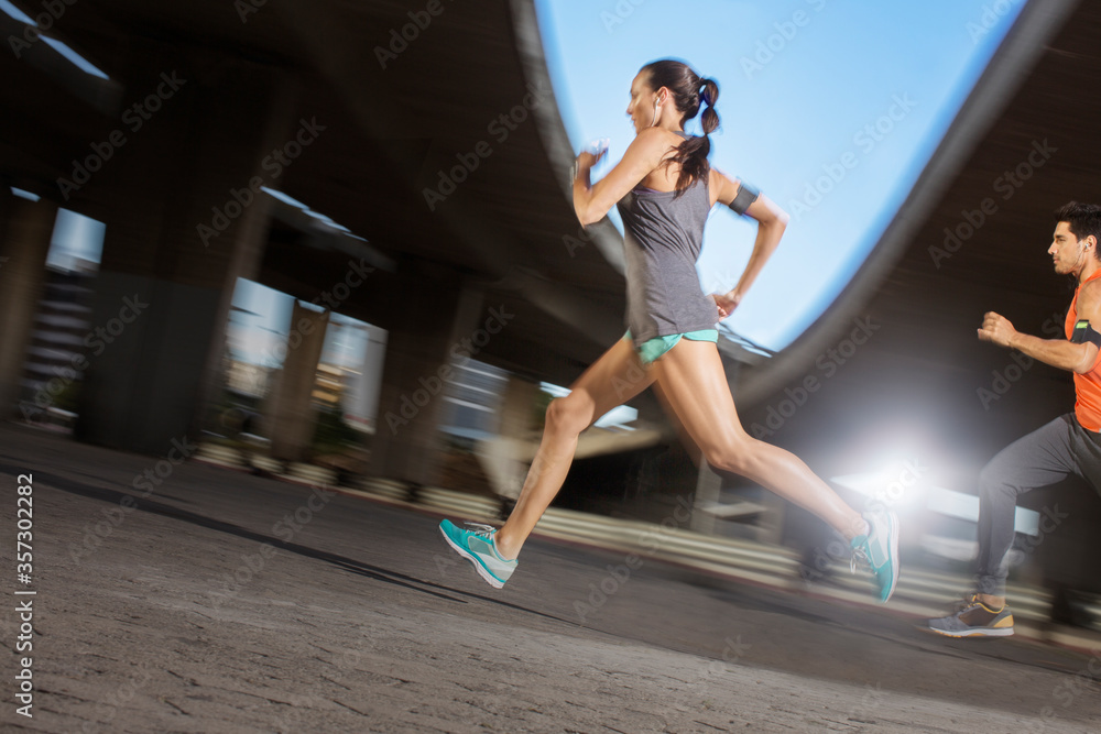 Fototapeta premium Couple running through city streets together