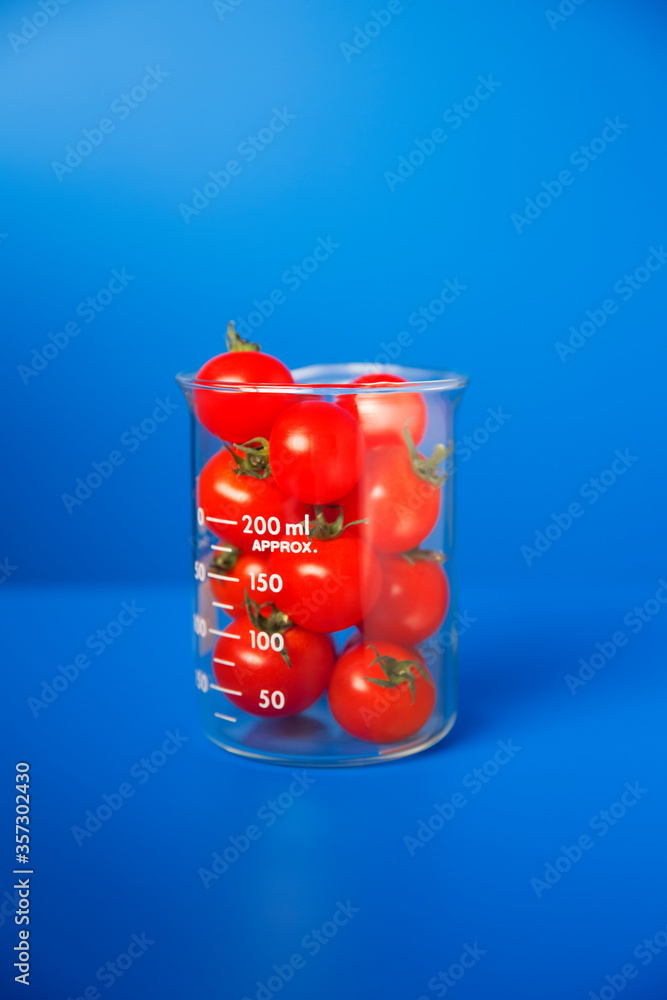 Obraz premium Beaker of small tomatoes on blue counter