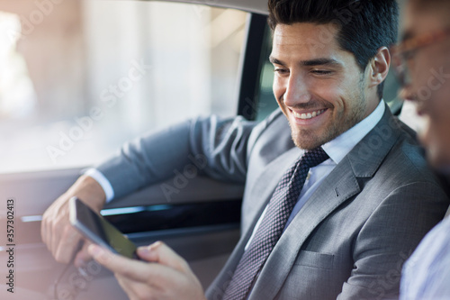 Businessmen looking at cell phone in car 