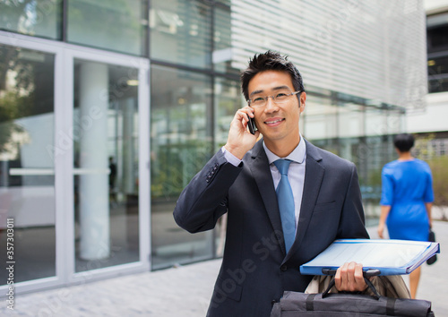 Businessman talking on cell phone outside of office building