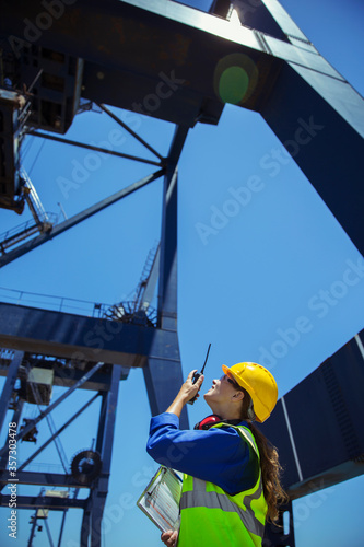 Low angle view of worker using walkie-talkie under cargo crane
