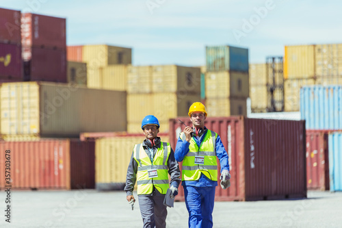 Worker and businessman walking near cargo containers