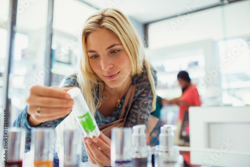 Woman examining skincare product in drugstore