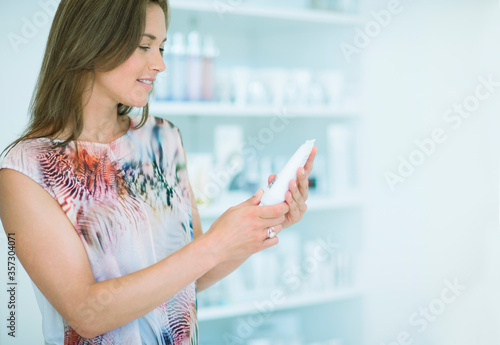 Free Download Woman examining skincare product in drugstore - GFXLoad