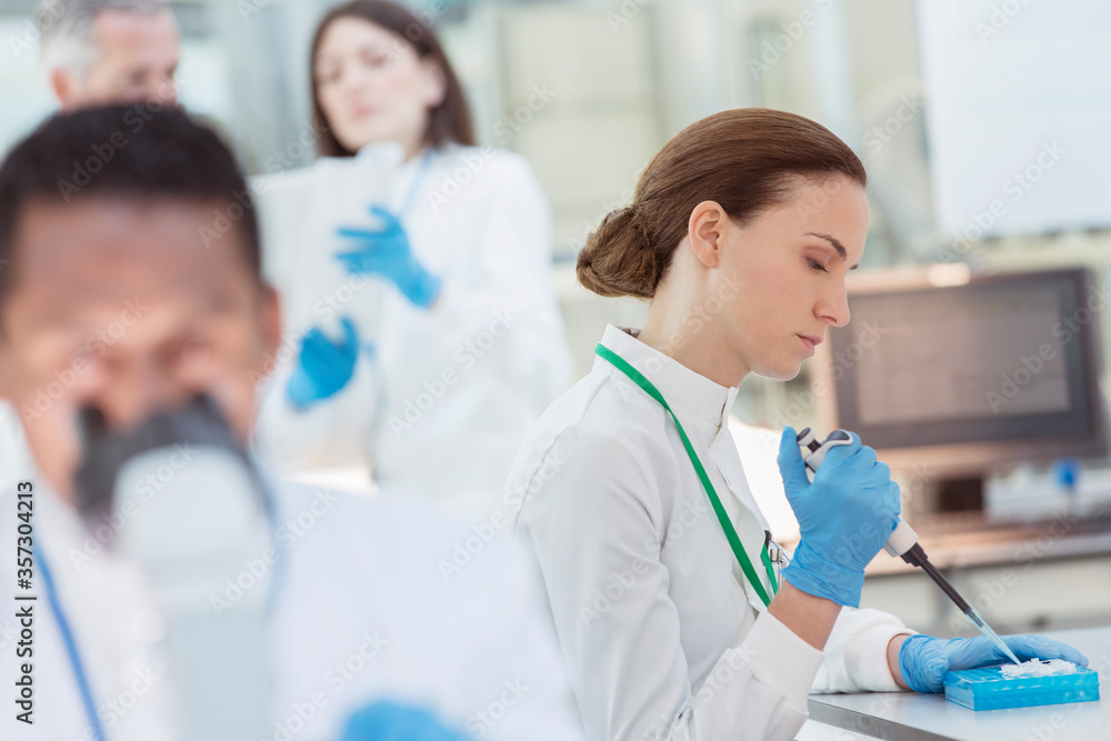 Scientist pipetting sample into tray in laboratory Scientist pipetting sample into tray in laboratory