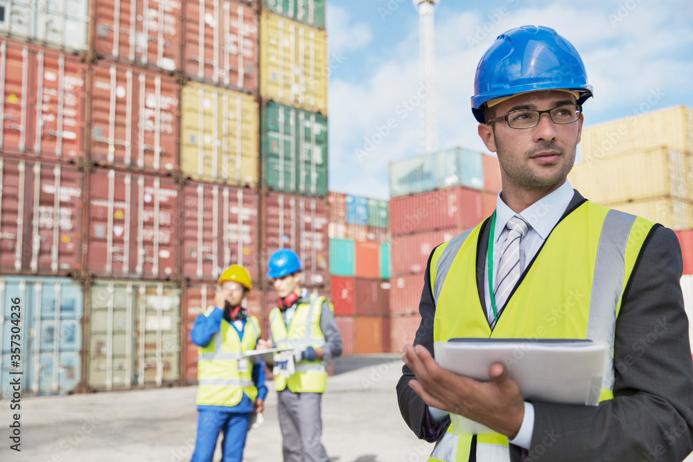 Businessman using digital tablet near cargo containers
