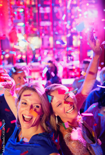 Confetti falling on two women dancing back to back in nightclub