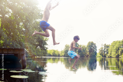 Father and son jumping into lake photo