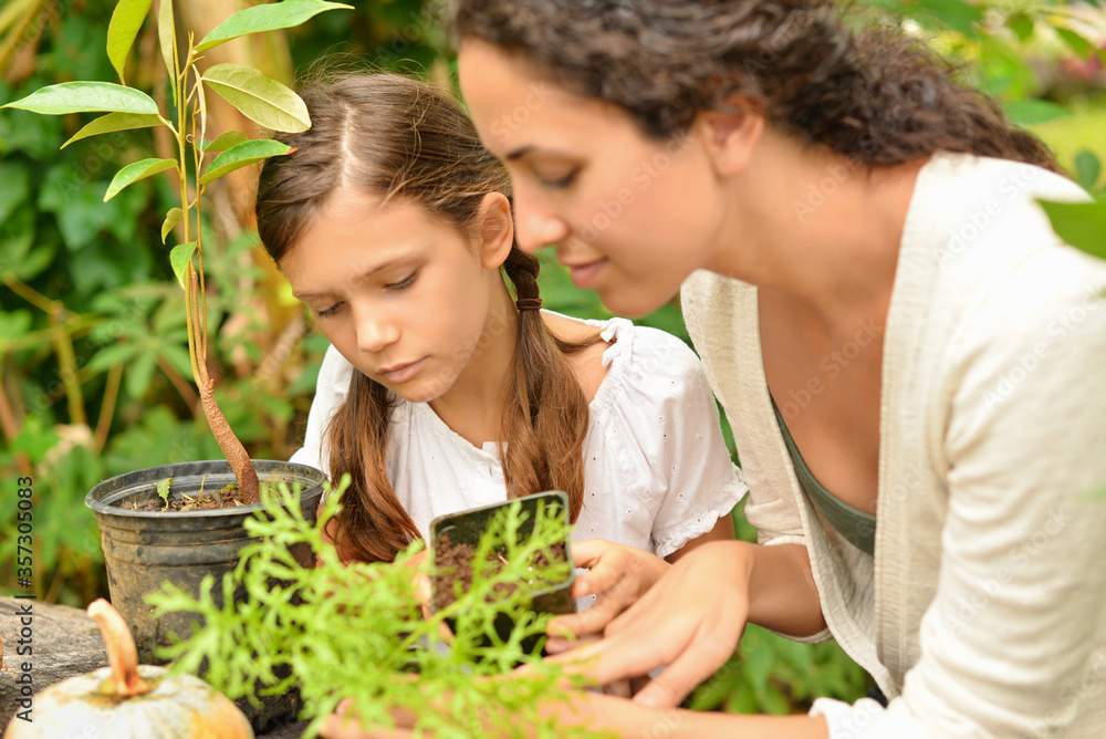 Obraz premium Woman and girl potting plants in garden