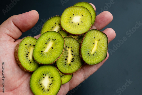 close up on sliced ​​fruit kiwi on palm, black background