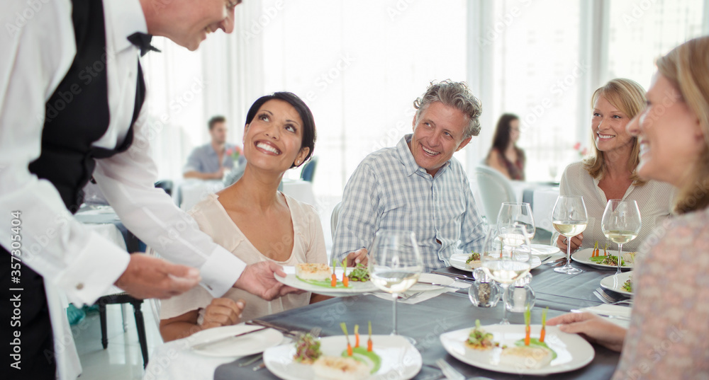 Waiter serving fancy dish to woman sitting at restaurant table Waiter serving fancy dish to woman sitting at restaurant table